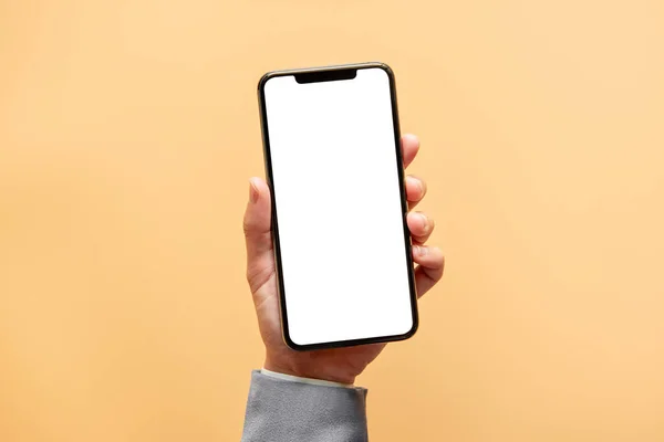 Akıllı telefon maketi. Sarı arka planda siyah telefon beyaz ekranını tutarak elinizi kapatın. Cep telefonu çerçevesiz tasarım kavramı.