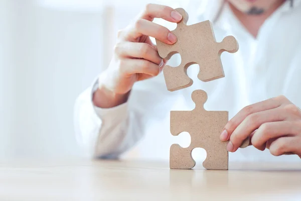 Business solutions partnership and strategy concept, Businessman hand connecting jigsaw puzzle on desk.