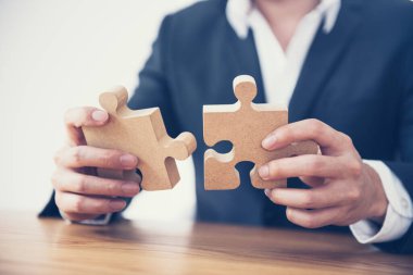 İş çözümleri ortaklığı ve strateji konsepti, İşadamı eli yapbozu masa üzerine bağlıyor.