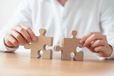 İş çözümleri ortaklığı ve strateji konsepti, İşadamı eli yapbozu masa üzerine bağlıyor.
