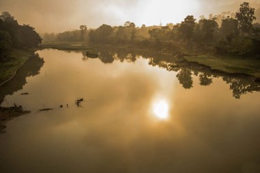 Kaziranga Ulusal Parkı, Assam, Hindistan 'da gün doğumunda dağların, ağacın ve sislerin manzarası.