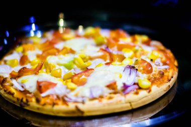 Fresh Homemade cheese pizza, with tomato, onion, corn toppings, with selective focus in lockdown.