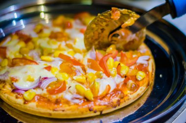 Fresh Homemade cheese pizza, with tomato, onion, corn toppings, with selective focus in lockdown.
