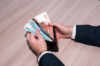 Erkek bir çanta çıkarır. Büyük banknotlar.