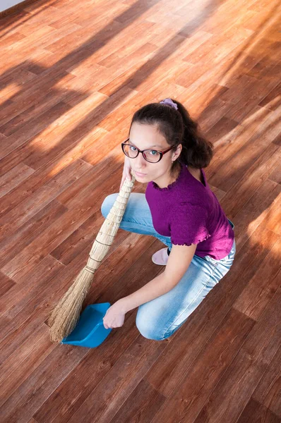 Kız yerdeki faraş parçalarını süpürüyor.