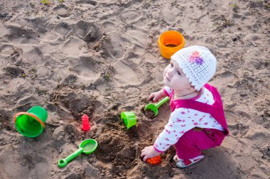 Yılın çocuğu kum havuzunda oynuyor.
