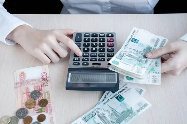 Masadaki kız hesap makinesiyle kârı düşünüyor.