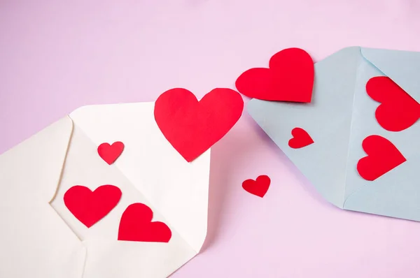 Valentine\'s day card: two envelopes with red hearts on a pink background