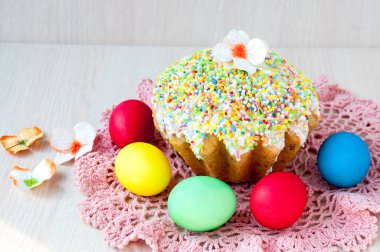 Masadaki Paskalya pastası pembe peçete ve renkli yumurtalar.