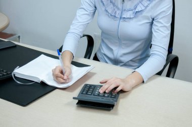Ofis, esmer muhasebeci kız masasında hesap makinesiyle çalışıyor.