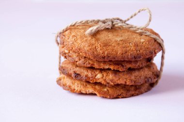 Pembe arka planda iple bağlanmış yulaflı kurabiyeler.