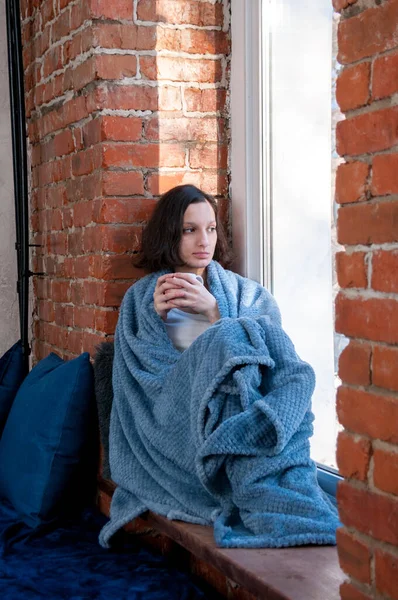 秋の窓辺の窓辺には毛布に包まれたお茶の女の子 快適さと暖かさの概念 — ストック写真