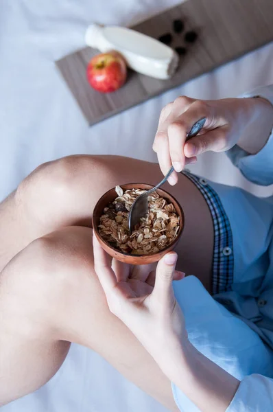 침대에서 식사를 파란색 셔츠를 소녀가 우유를 곁들인 곡물식을 — 스톡 사진