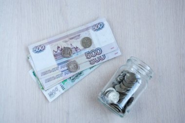 Cam bir kavanozda bozuk paralar ve masada büyük Rus banknotları. Yatırım konsepti, ilgi
