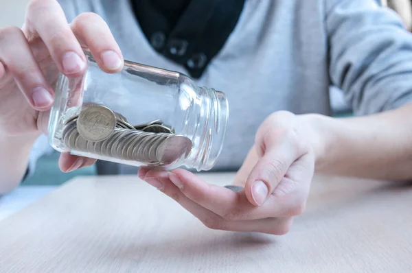Kadınların elleri cam bir kavanozdan masaya para dökerler. Biriktirme kavramı