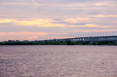 Amur nehrinde gün batımı, Khabarovsk şehrinde nehir üzerinde bir yol köprüsü olan manzara.