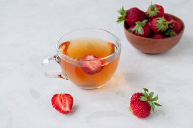 Masada bir fincan çilek çayı ve bir kase çilek.