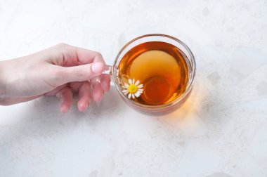 Masada bir fincan papatya çayı tutarken.