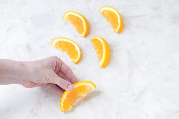 Kadınların elleri, sulu portakal dilimlerini masanın üzerinde tutuyor.