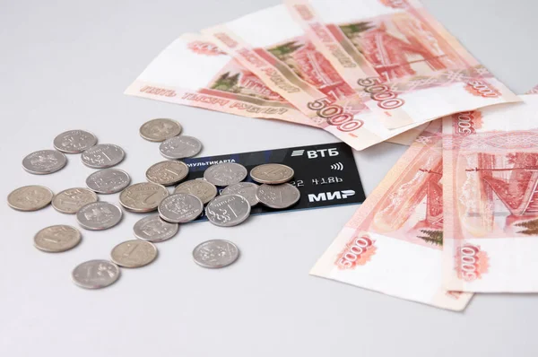 Birçok küçük Rus sikkesi, beş bin dolarlık banknotlar ve gri arka planda bir banka kartı, bankalarda mevduat kavramı