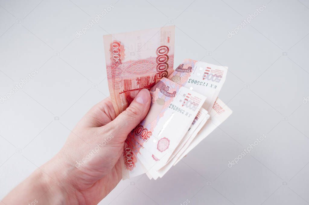 A woman's hand holds large Russian bills, a concept of salary