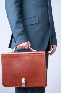 Kahverengi evrak çantası tutan takım elbiseli bir adam.