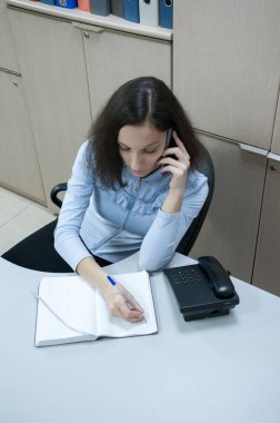 Ofis, esmer kız müşterilerle telefonda konuşuyor.