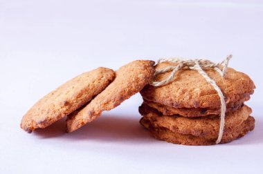 Pembe arka planda iple bağlanmış yulaflı kurabiyeler.