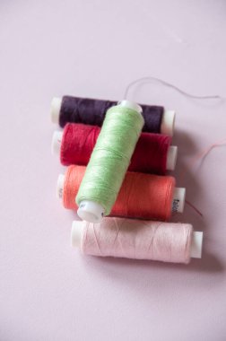 Pembe arka planda güçlendirilmiş farklı renk iplikleri dikiliyor