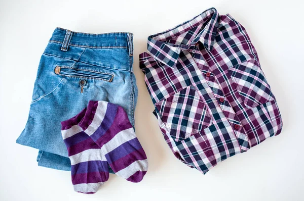 Giysiler, katlanmış ekose gömlek ve kot pantolon, açık arkaplanda çizgili çoraplar.