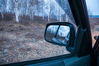 Arabanın yan aynası, kapıdan dışarı bakıyor.