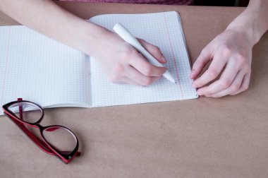 Kadın eli, defter kalemine kırmızı gözlük yazar.