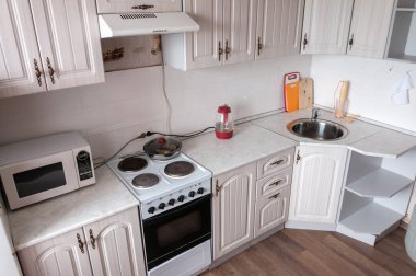 İç bej rengi küçük bir mutfak, dolaplar, elektrikli soba.