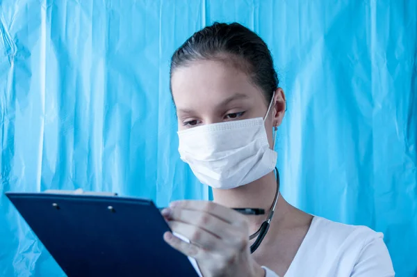 Girl doctor in mask writes prescription for treatment