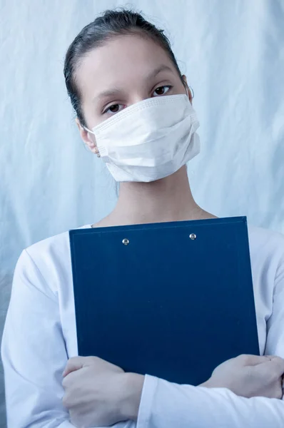 The brunette girl doctor in a mask is holding a folder