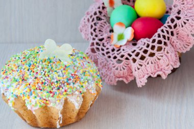 Renkli yumurtalar ve Paskalya pastasıyla dolu sepette pembe peçete.