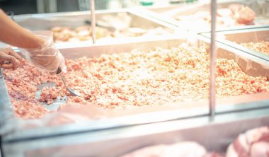 Süpermarket çalışanı bir süpermarkette seçilen tüketiciler için taze domuz etini sergi tepsisinde hazırlıyor.. 