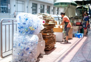 Küresel ısınma ve çevre konsepti için geri dönüşüm ve yeniden kullanım için ayrılan el arabasında ve şişe yığınında düzleştirilmiş karton kutular..
