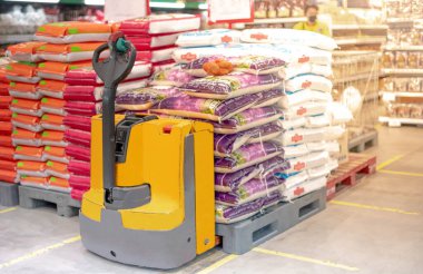 İçinde pirinç torbası olan el arabası ve toptan fiyatına satılan plastik paletler. Süpermarket için ürünleri indiriyorum. Ticaret ve lojistik.