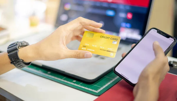 Hand holding credit card and mobile phone, The credit card prepare for customer and entrepreneur using for online shopping, e-commerse, business and internet banking with laptop.