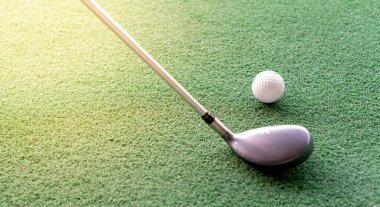 Golf sopası ve beyaz golf topu golf sahasına konur ve golf kulübüne vurmaya hazırlanır..