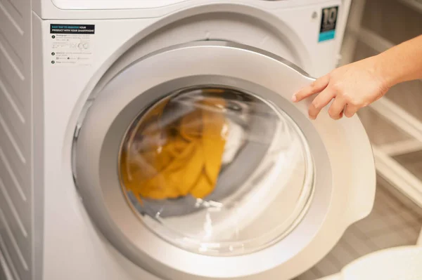 Female hand opening the washing machine prepare wash the clothes, for the hygience and cleaning.