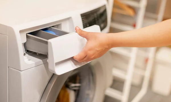 Female hand opening the washing machine and the space for detergent liquid preparing wash the clothes, for the hygience and cleaning.