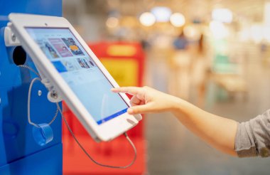 Bulanık arka planı olan müşteriye ürünün bilgilerini veya tanımını almak için tablet monitörüne dokunan kadın el kamuya açık alanda.