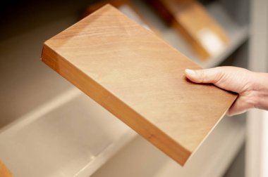 Kadın el, ev içi mağazanın ahşap kapısının örnek renk plakasını tutuyor..