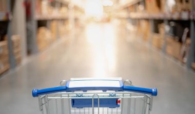 Büyük depo koridorunda içi boş gümüş ve mavi alışveriş arabası ile bulanık efekt. Alışveriş yapan kişi evin iç tasarımı için mobilyaları seçiyor. İç tasarım konsepti için.