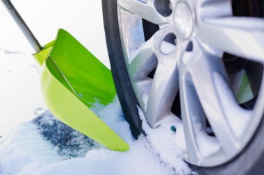 Bir adam yolu hazırlamak için tekerlek kenarına kar kürüyor..