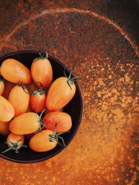Sarı küçük kirazlar pomimidors, yuvarlak bir tabakta yatar. Parlak sarı-kahverengi arka plan. Güzel pas. Hasat et. Doğal yiyecekler. Sağlıklı beslenme vitaminleri
