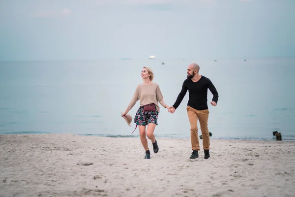 Gelukkig jong stel veel plezier op het strand, hand in hand. — Stockfoto