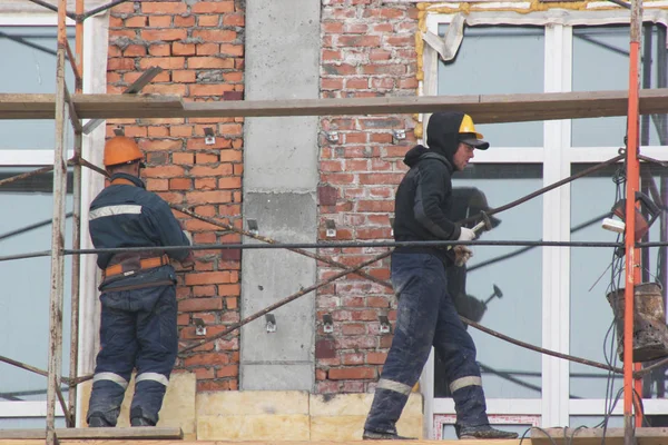 Trabajadores parados en una escalera de madera en el bosque, reparando la pared del edificio Imagen De Stock